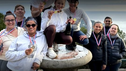 Équipe souriante médaillée lors d’Olympiades Team Building à Nice face à la mer